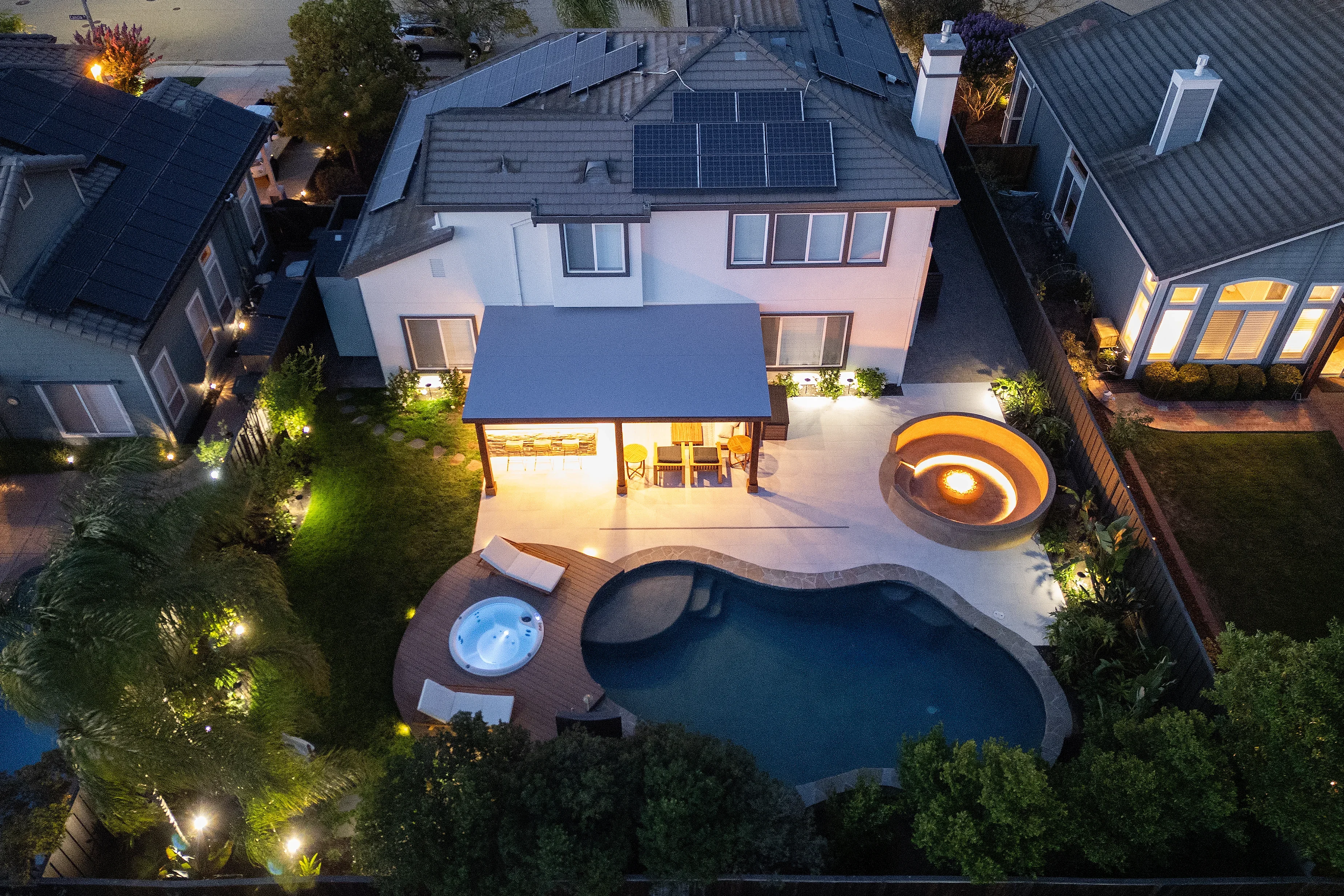 Aerial view of pool, spa, composite deck, concrete patio, pergola, and landscape lighting