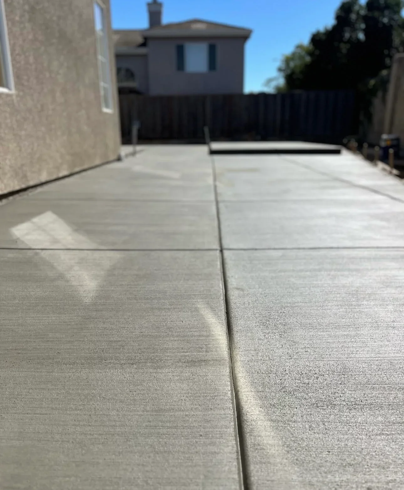 Newly installed concrete patio with control joints and broom finish in residential backyard