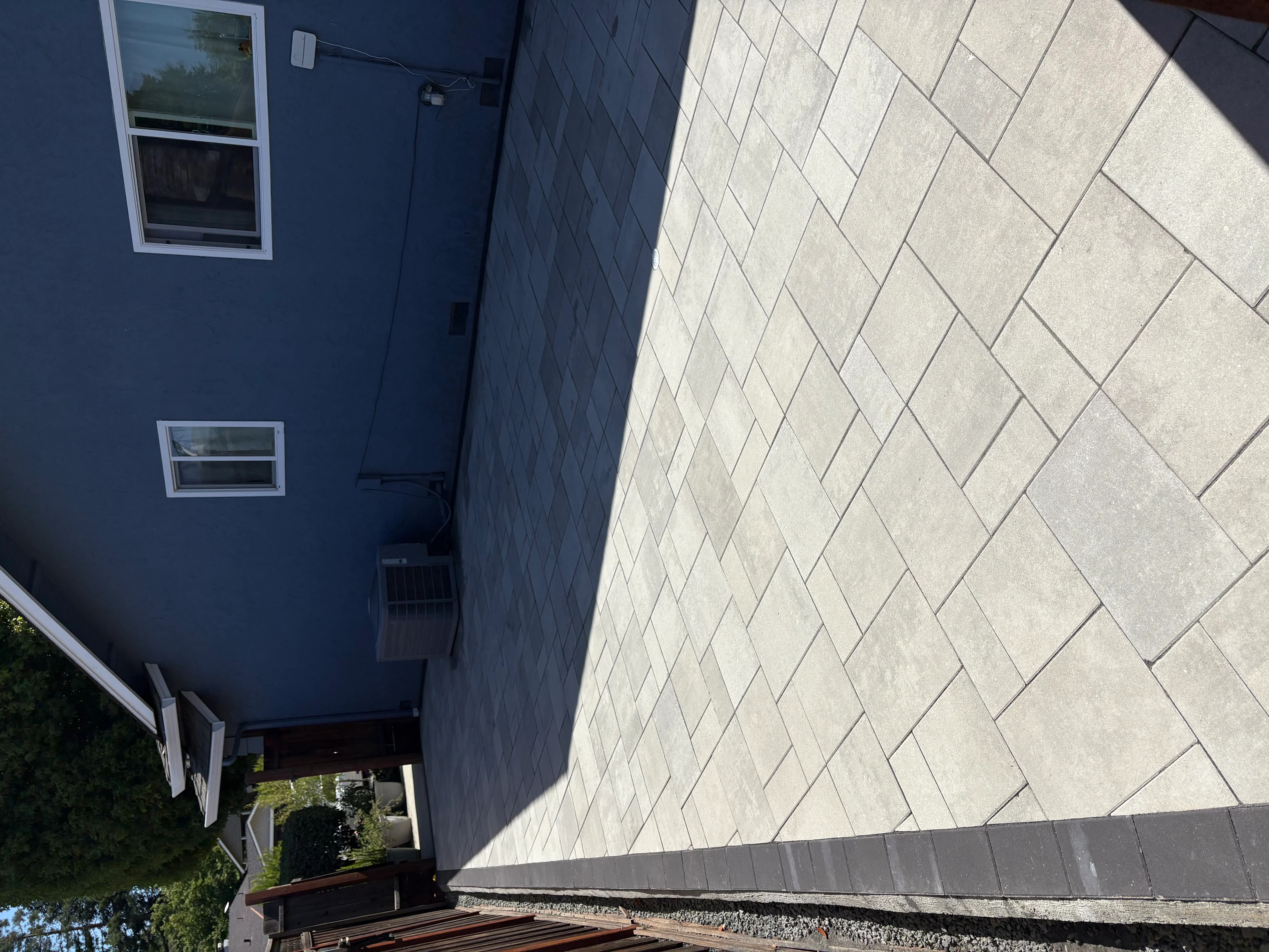 Diagonal herringbone patio with light porcelain pavers and modern home exterior
