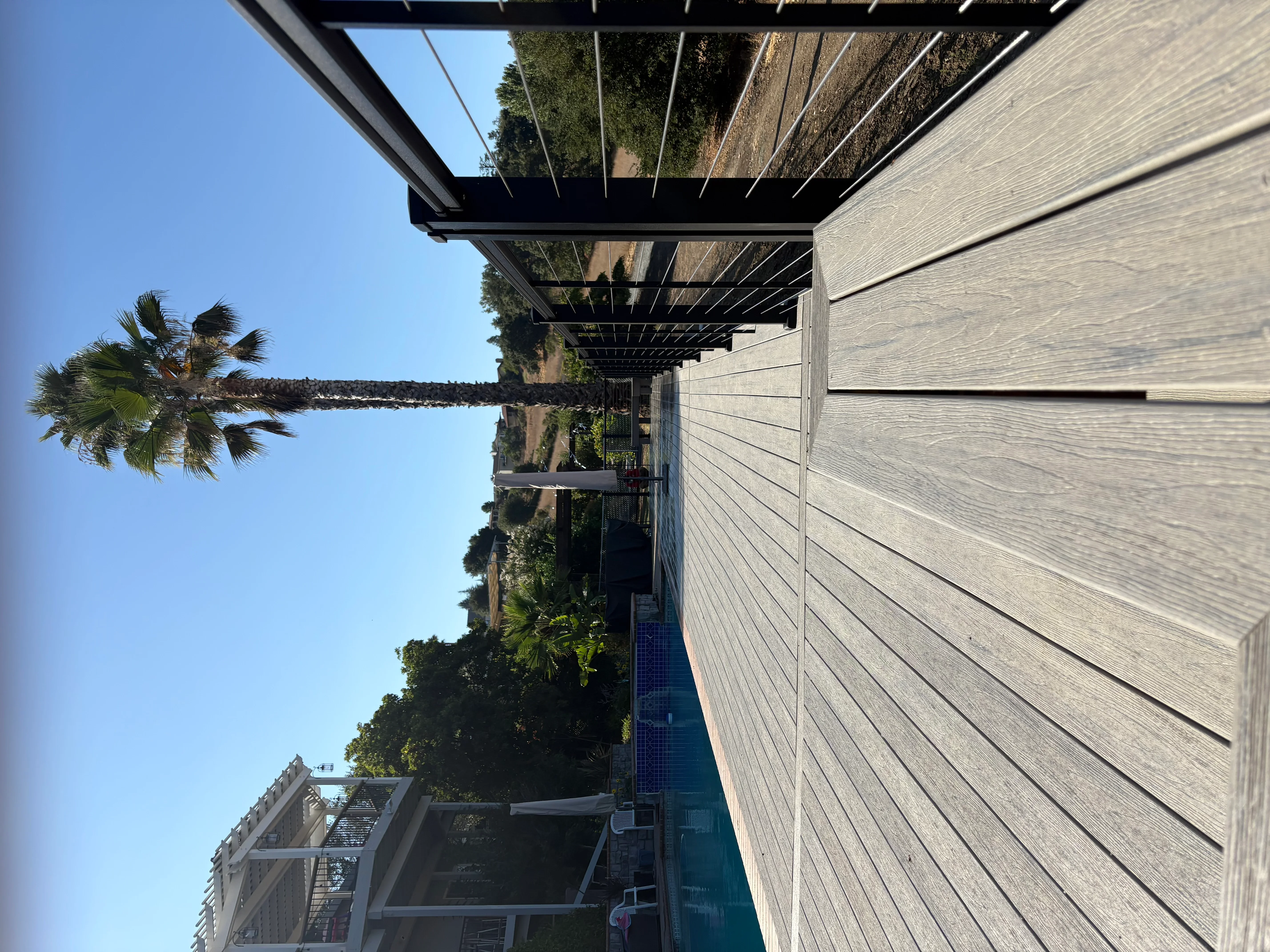 Modern pergola with retractable shade system over patio with palm trees