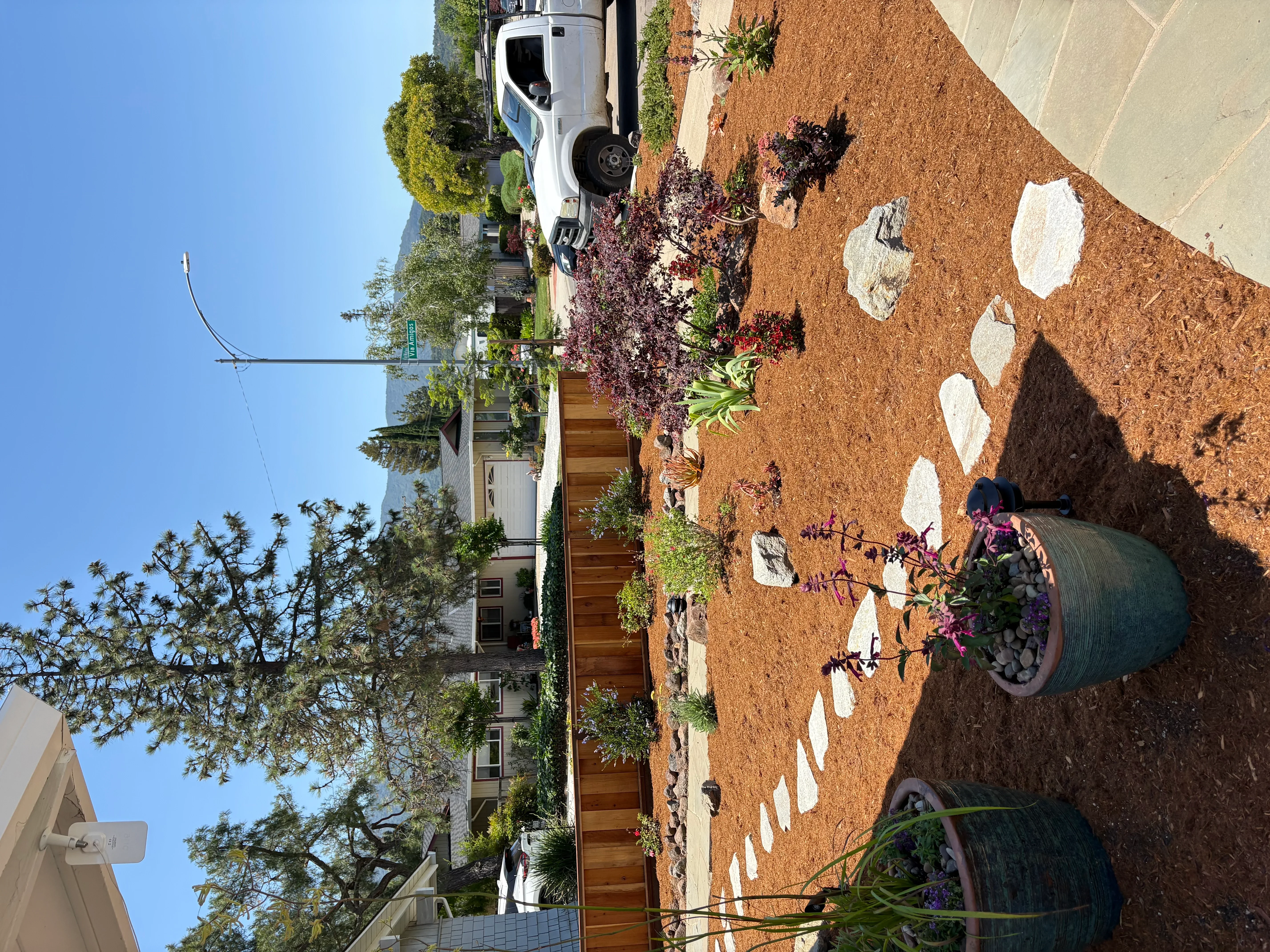 Residential driveway with mulch landscaping, white rock accents, and flowering plants