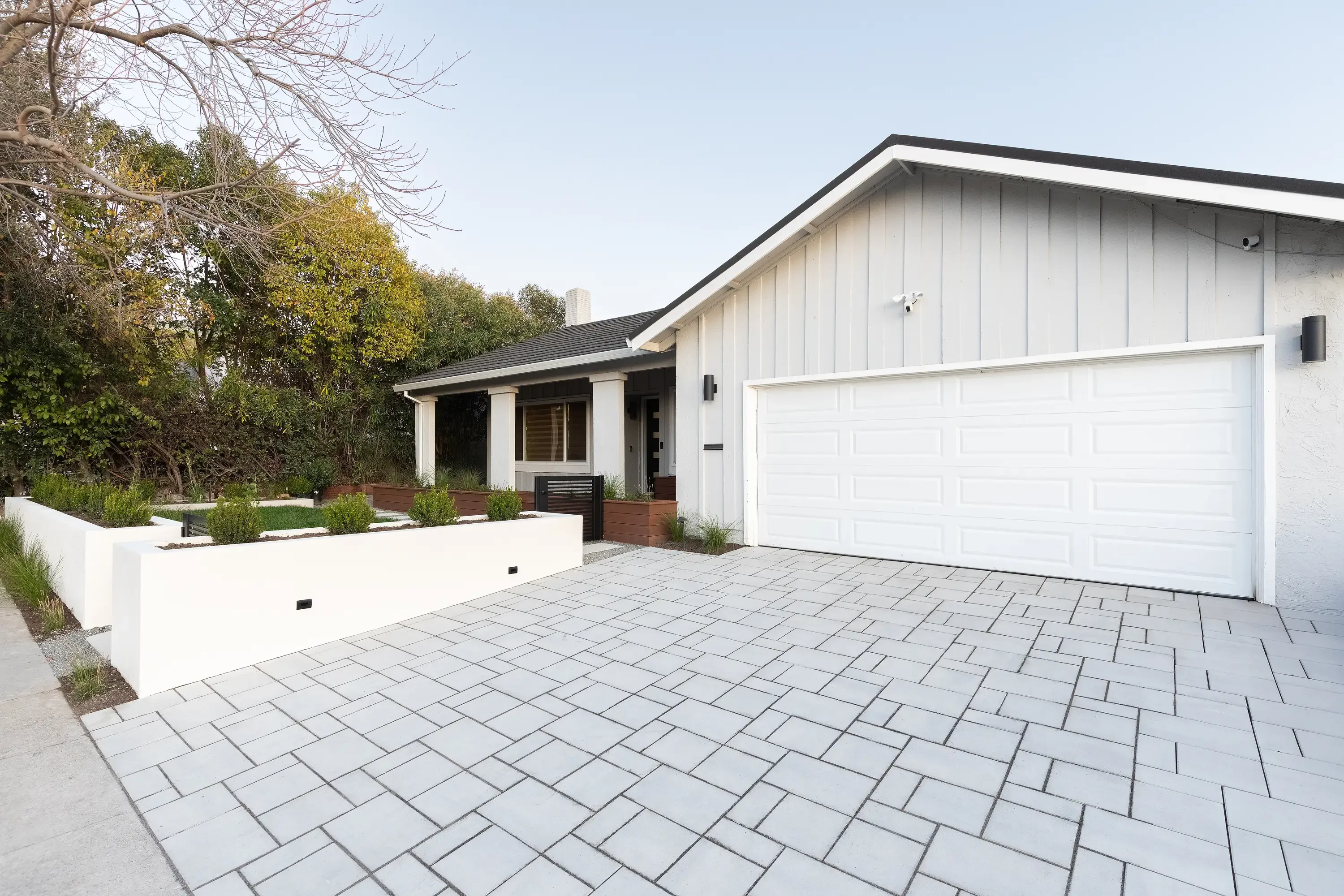 Modern home with light gray permeable pavers driveway and white raised planter bed