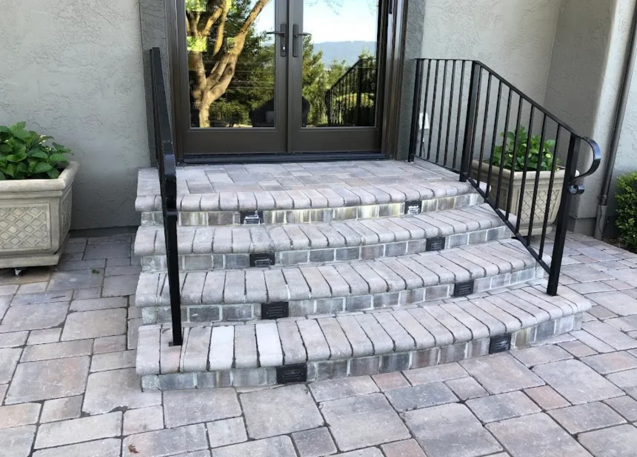 Curved brick steps with metal railings and integrated lighting leading to patio