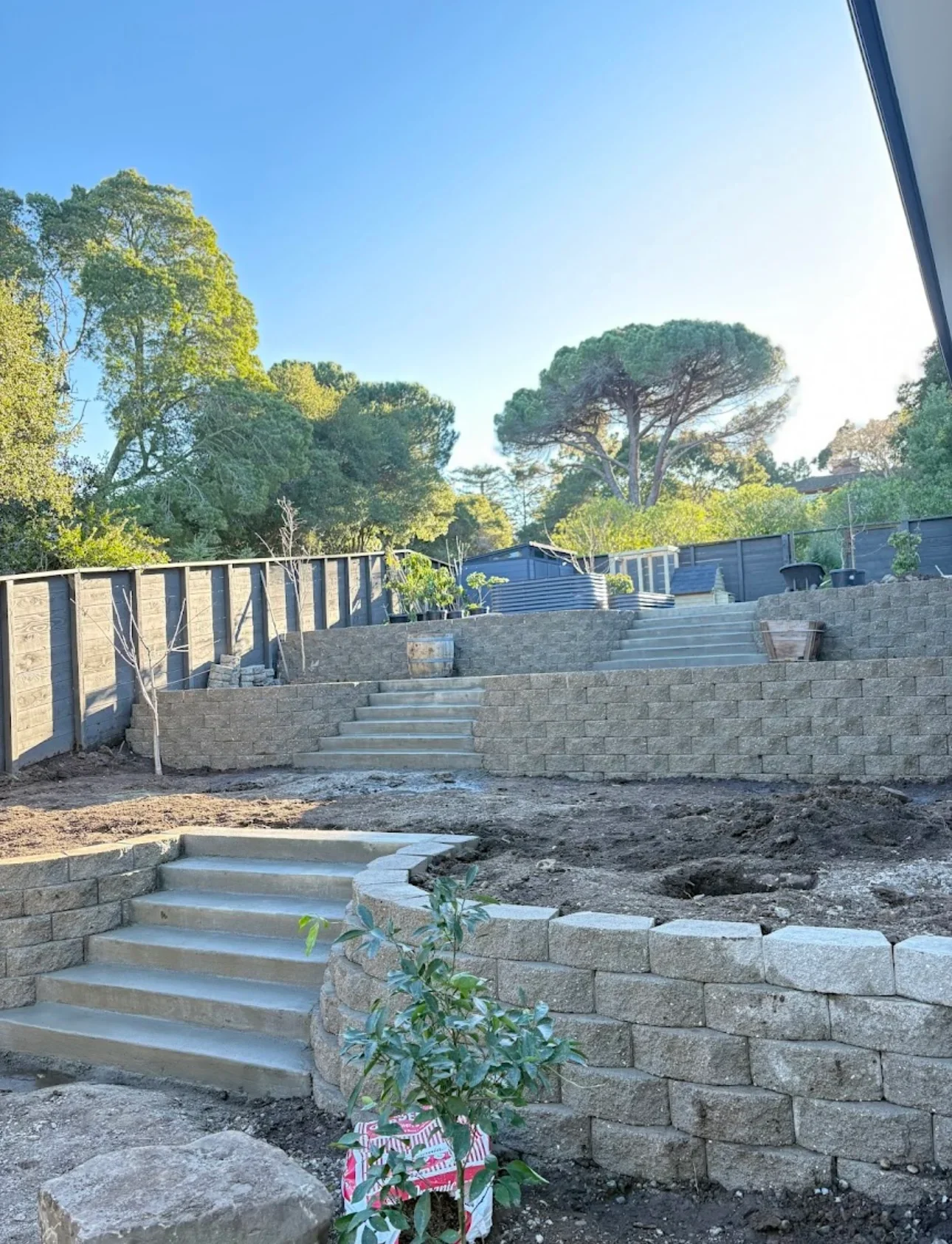 Tiered stone retaining walls with concrete stairs on sloped terrain
