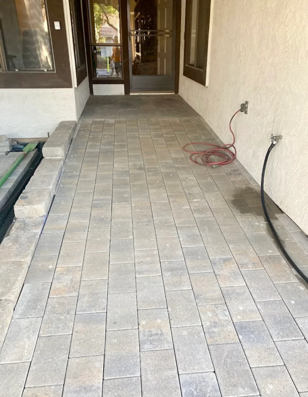 Newly installed rectangular patio tiles in running bond pattern on covered entry