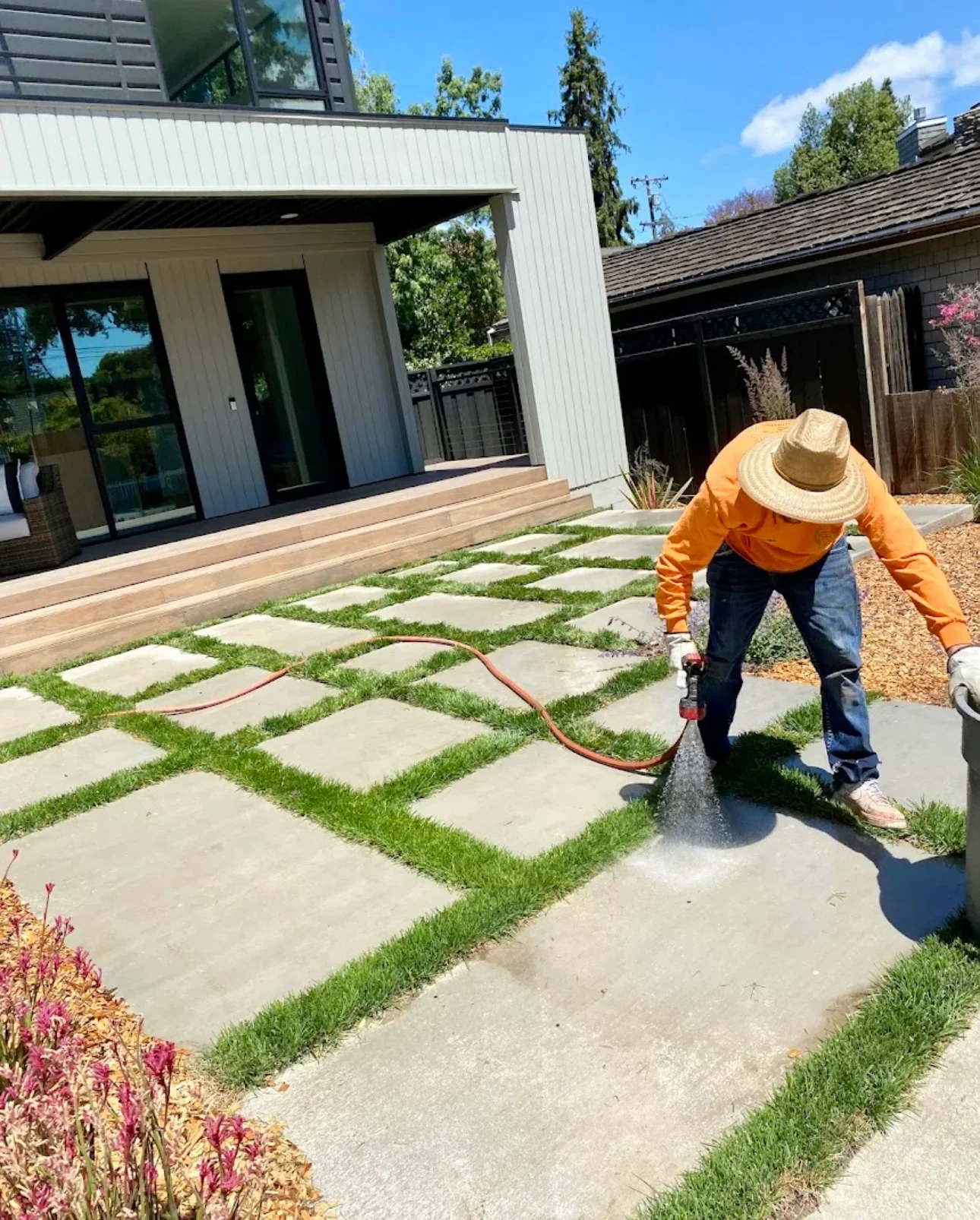 Worker installing concrete stepping stones with grass joints in modern residential landscape