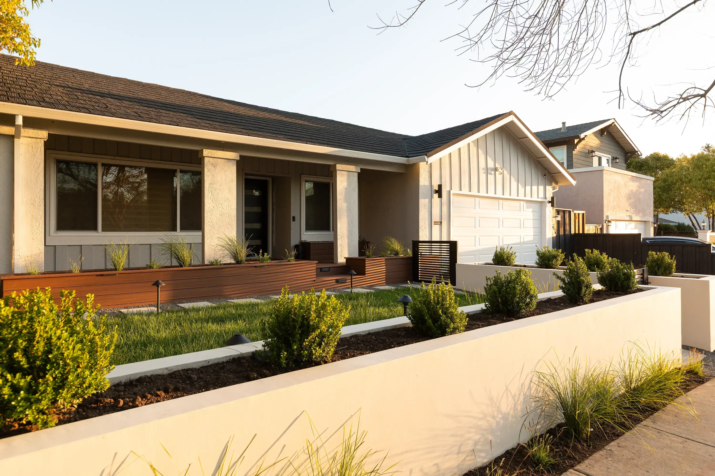 Modern home front yard with tiered concrete planters, ornamental grasses, and manicured shrubs